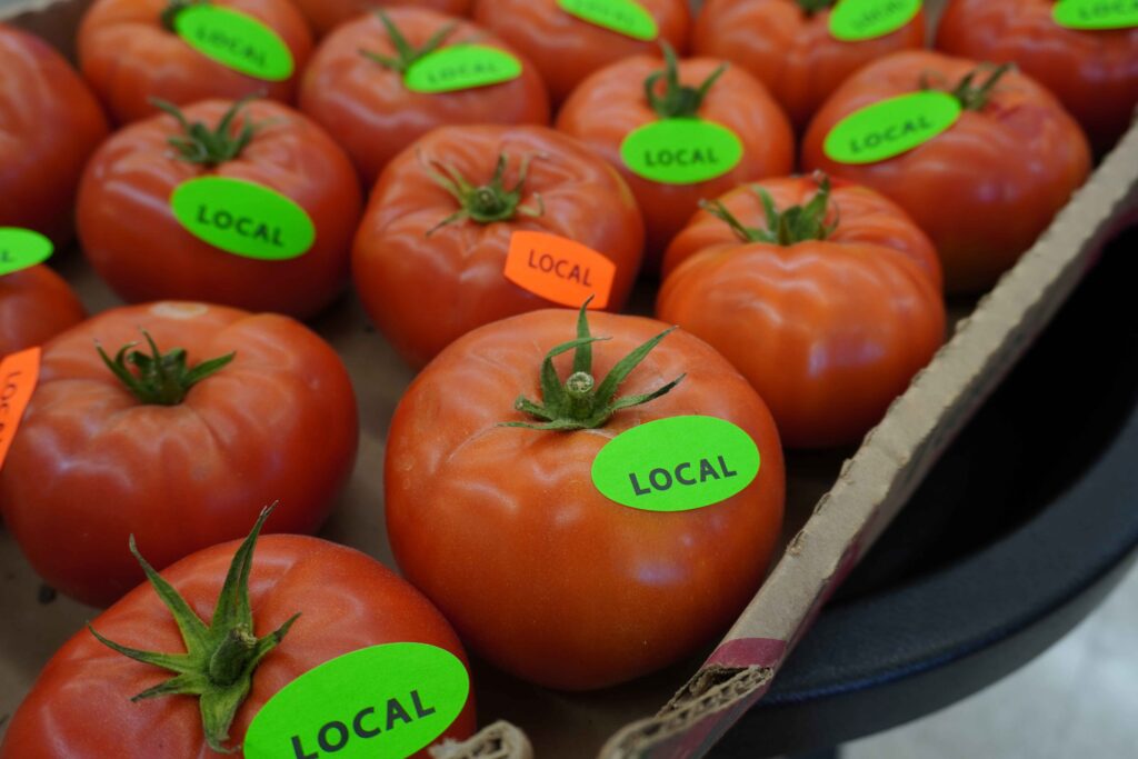 close up of tomatoes with green stickers that read 'LOCAL'